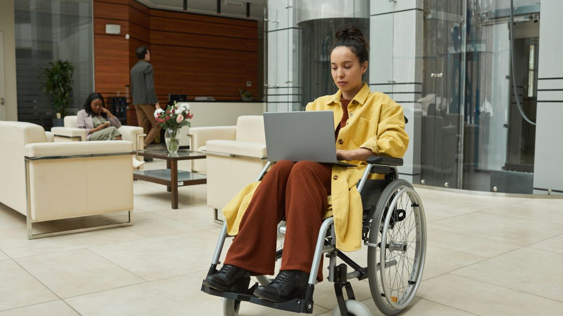 A person in a wheelchair with a laptop, researching about long term disability benefits