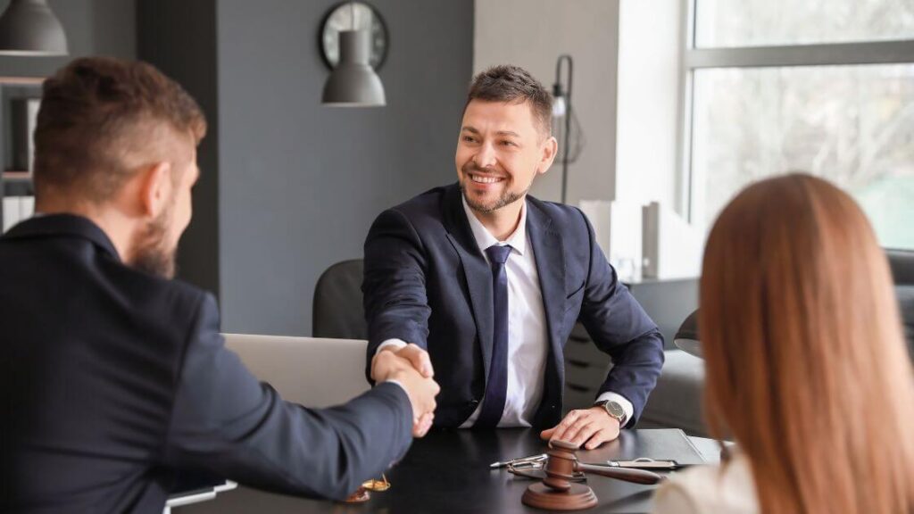 A person in a suit shaking hands with a lawyer, representing someone seeking legal advice for a wrongful dismissal case