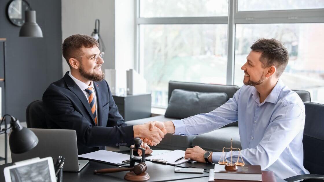 A person in a suit shaking hands with a lawyer, representing someone looking for a qualified employment lawyer